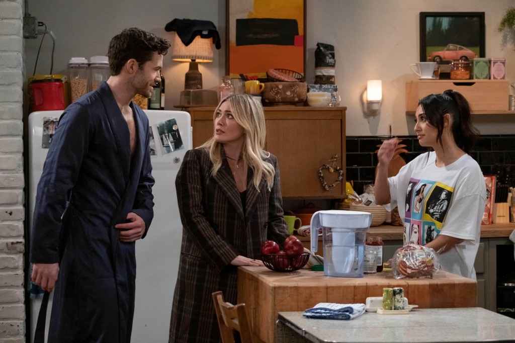 Tom Ainsley, Hilary Duff, and Francia Raisa stand in an apartment kitchen talking in "How I Met Your Father." 