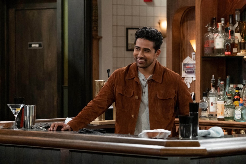 Sid (Suraj Sharma) smiles and stands behind a bar in "How I Met Your Father." 