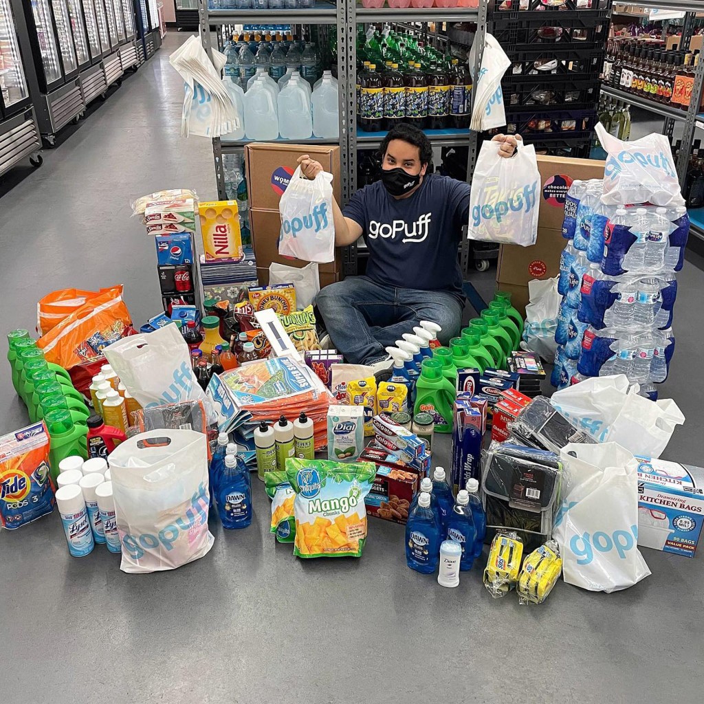 GoPuff employee sitting on the floor surrounded by groceries