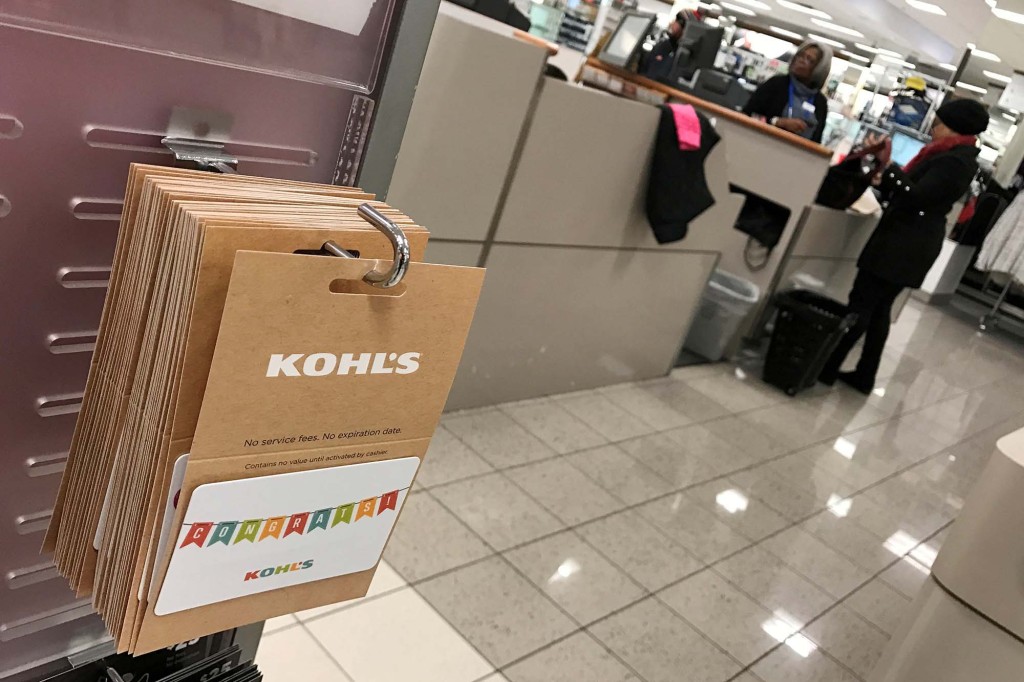 Kohl's gift cards seen inside a Kohl's with a shopper and salesperson in the background