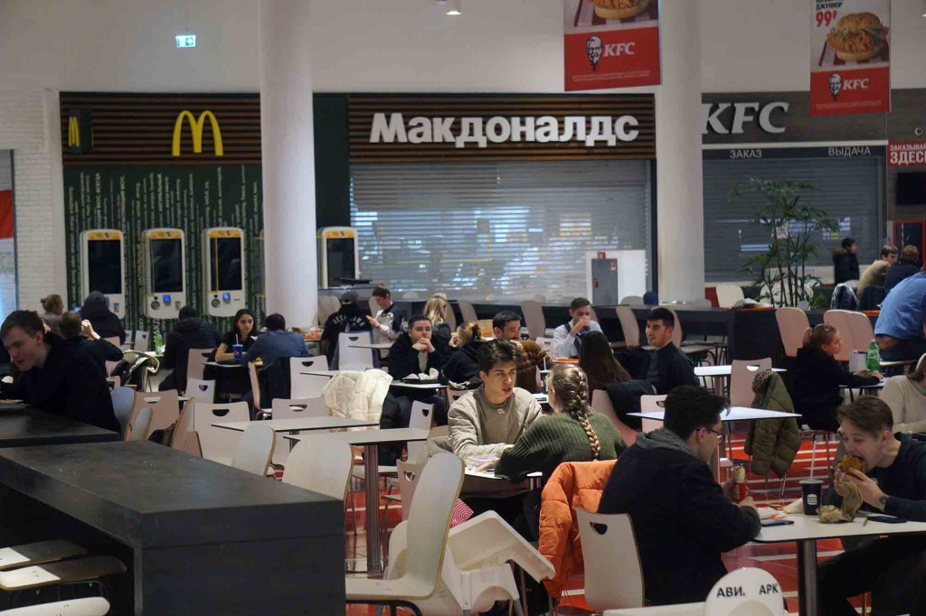 Diners sitting at tables inside a McDonald's restaurant in a shopping mall.
